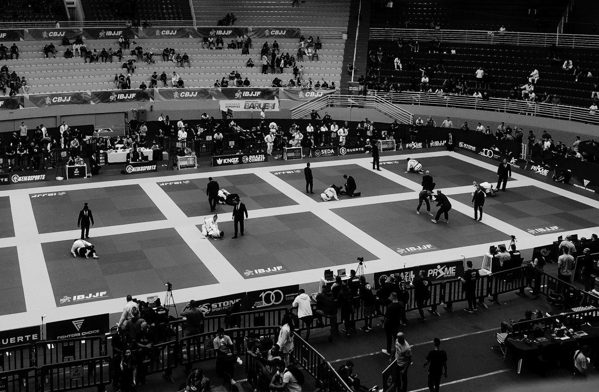 Arena de campeonato de jiu-jitsu com múltiplas lutas simultâneas